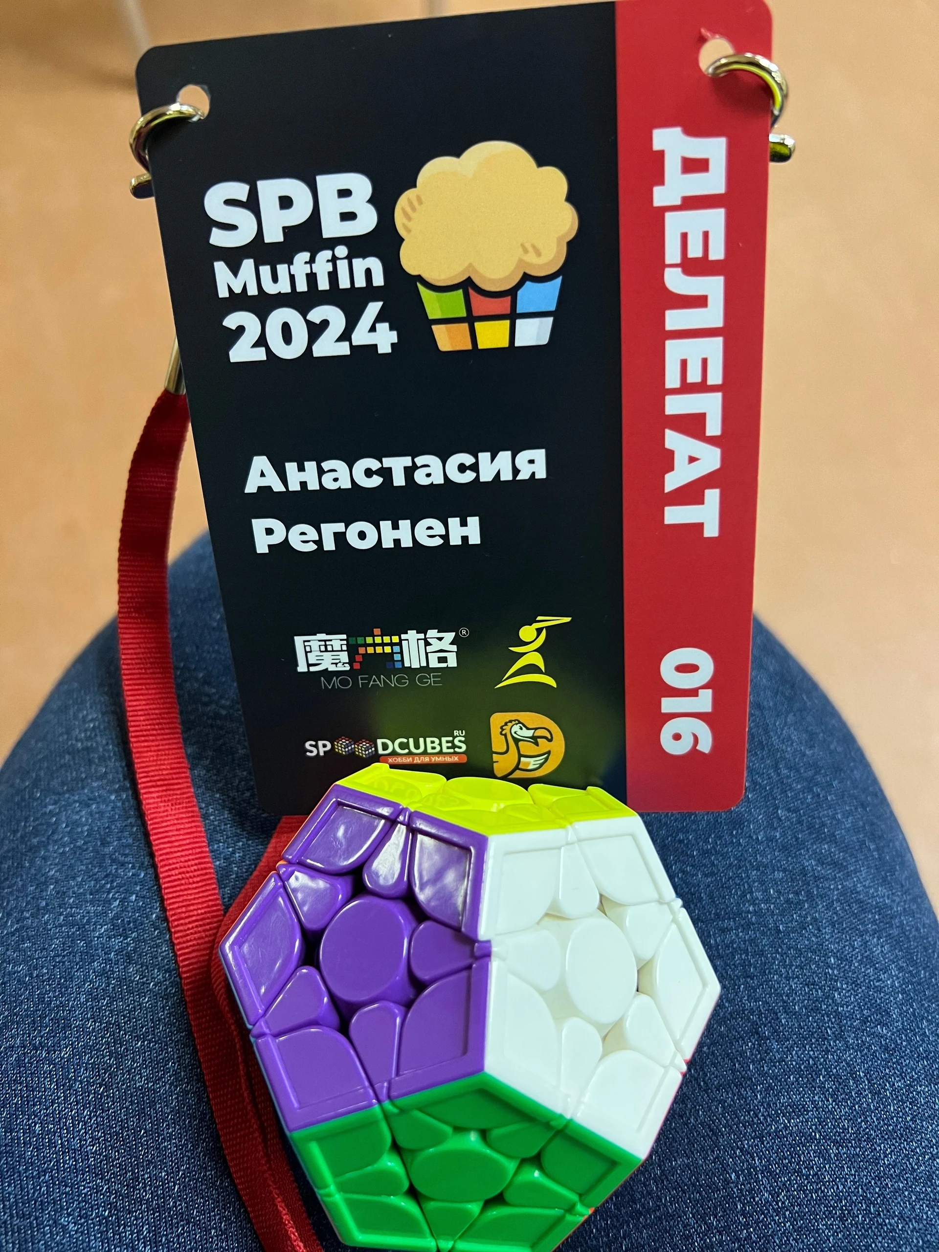 Бейдж Анастасии Регонен — делегата SPB Muffin 2024, рядом с мегаминксом